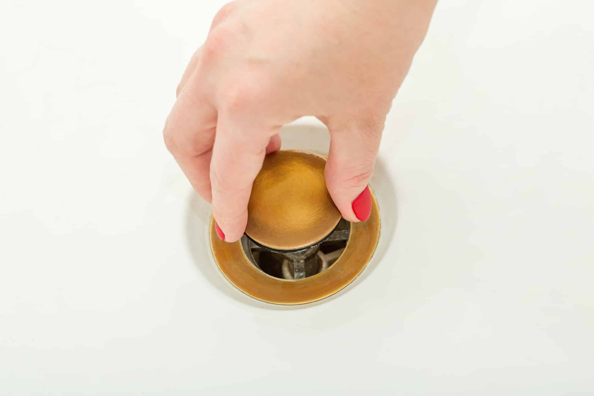 Female hand holds bathtub drain plug